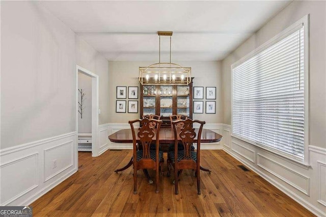 2508 Haddenham Ln SW, Smyrna, GA 30082 - dining area with a chandelier, wood finished floors, a decorative wall, and a wainscoted wall
