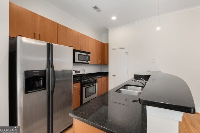 384 Ralph Mcgill Blvd NE Unit 123, Atlanta, GA 30312 - kitchen featuring stainless steel appliances, ornamental molding, a peninsula, brown cabinets, and dark stone counters