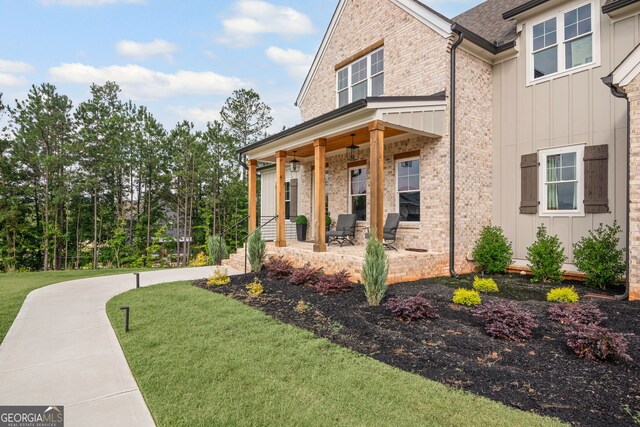 40 Fernbank Way, Newnan, GA 30265 - view of front of home featuring board and batten siding, a porch, a front lawn, brick siding, and a shingled roof