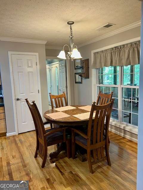 370 Butler Path, Dallas, GA 30132 - dining area featuring light wood-style floors, a textured ceiling, crown molding, and a chandelier