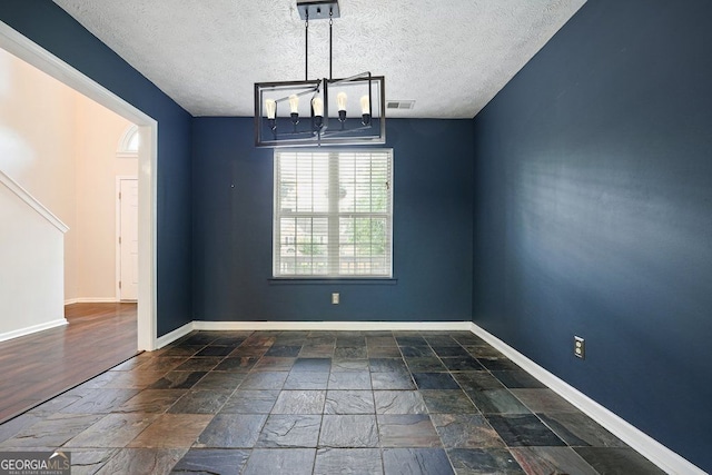 3366 English Oaks Dr NW, Kennesaw, GA 30144 - unfurnished room featuring a textured ceiling, stone tile flooring, and a chandelier