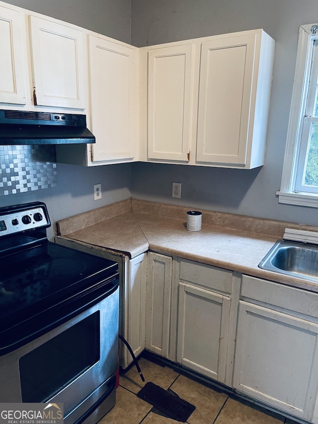 294 Pursley St, Macon, GA 31201 - kitchen with stainless steel electric range, under cabinet range hood, white cabinets, and light tile patterned floors