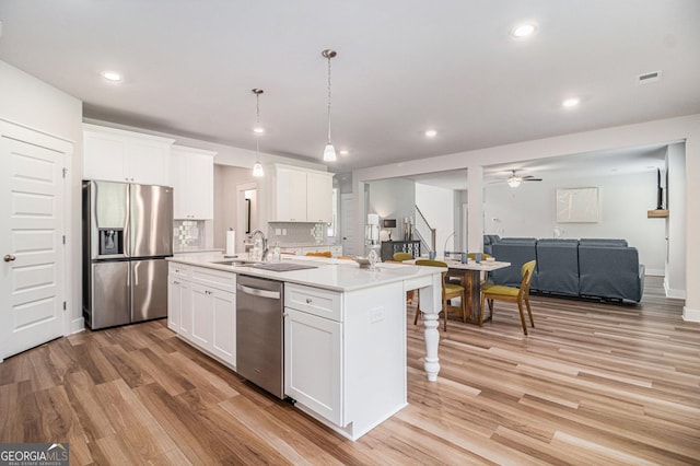 2 Whites Pond Rd, Moreland, GA 30259 - kitchen featuring appliances with stainless steel finishes, open floor plan, a center island with sink, light wood-style flooring, and white cabinetry