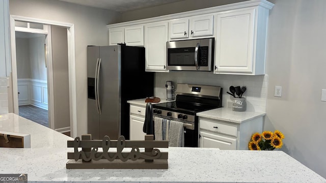 3066 Gem Creek Rd, Buford, GA 30519 - kitchen with appliances with stainless steel finishes, white cabinetry, backsplash, and light stone counters