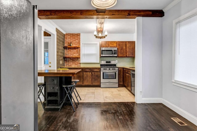1747 Parkhill Dr, Decatur, GA 30032 - kitchen with stainless steel appliances, beam ceiling, light wood finished floors, a chandelier, and hanging light fixtures