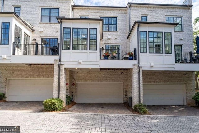 18 Peachtree Ave NE Unit 5, Atlanta, GA 30305 - back of property featuring a garage, brick siding, a balcony, and driveway