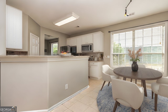 24 Arendt Park Ln, Newnan, GA 30263 - kitchen with stainless steel microwave, light tile patterned floors, white cabinetry, backsplash, and light countertops