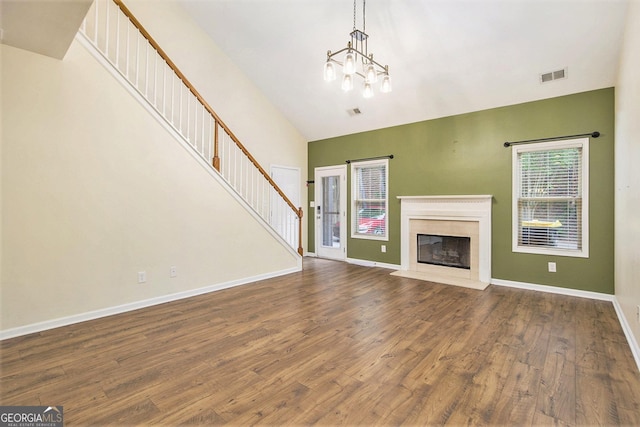 113 Macalester Dr, Newnan, GA 30265 - unfurnished living room with wood finished floors, high vaulted ceiling, stairway, a premium fireplace, and a chandelier
