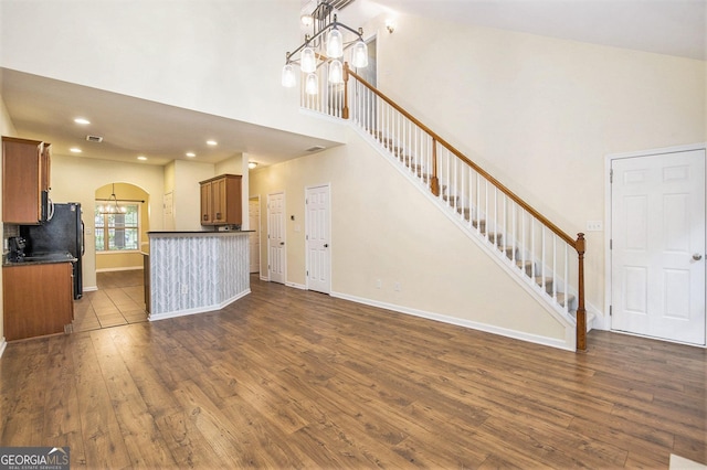 113 Macalester Dr, Newnan, GA 30265 - unfurnished living room with a chandelier, a high ceiling, dark wood finished floors, stairway, and arched walkways
