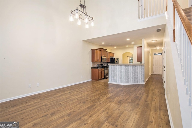 113 Macalester Dr, Newnan, GA 30265 - unfurnished living room with stairs, dark wood-style floors, a towering ceiling, and arched walkways