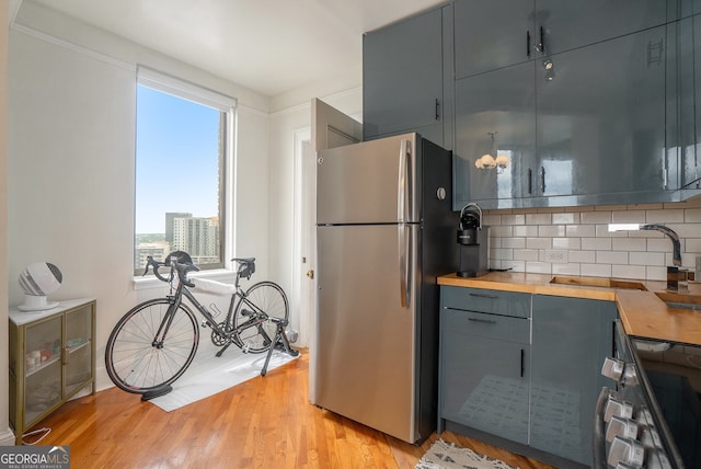 75 Ponce De Leon Ave NE Unit 1004, Atlanta, GA 30308 - kitchen with freestanding refrigerator, butcher block countertops, tasteful backsplash, range, and light wood finished floors