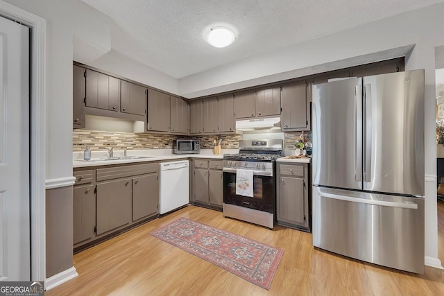 289 Westland Way SW, Marietta, GA 30064 - kitchen with appliances with stainless steel finishes, under cabinet range hood, light countertops, decorative backsplash, and light wood-type flooring