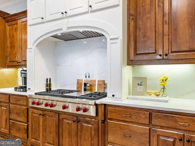 2392 Crimson King Dr, Braselton, GA 30517 - kitchen featuring stainless steel gas cooktop, arched walkways, light countertops, and white cabinetry