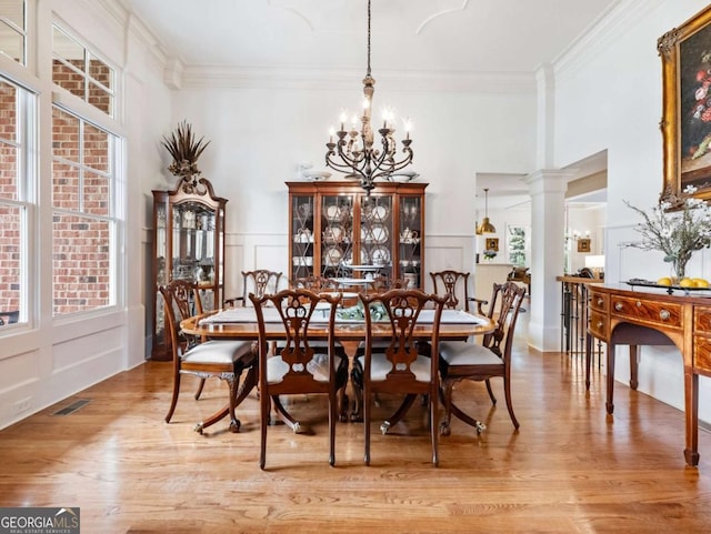 2392 Crimson King Dr, Braselton, GA 30517 - dining area featuring a chandelier, a decorative wall, light wood-style floors, crown molding, and decorative columns