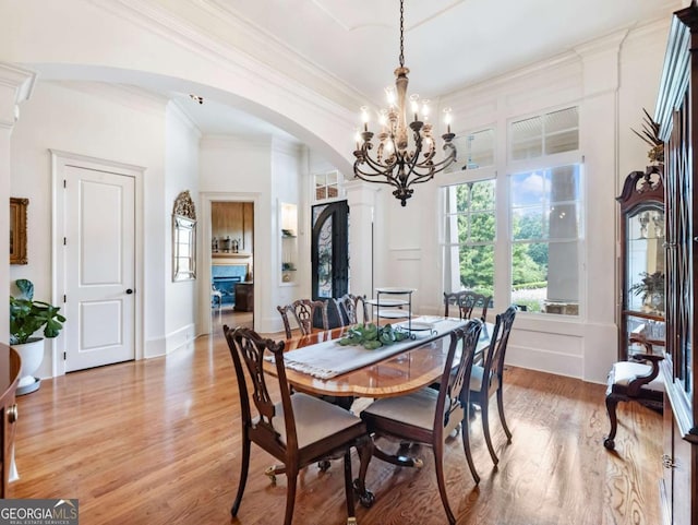 2392 Crimson King Dr, Braselton, GA 30517 - dining space featuring arched walkways, ornamental molding, a chandelier, and light wood-type flooring