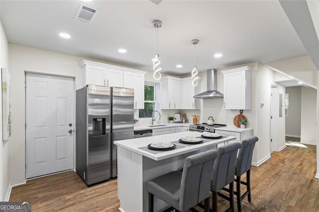1270 Graymont Dr, Atlanta, GA 30310 - kitchen featuring wall chimney exhaust hood, appliances with stainless steel finishes, white cabinets, light countertops, and wood finished floors