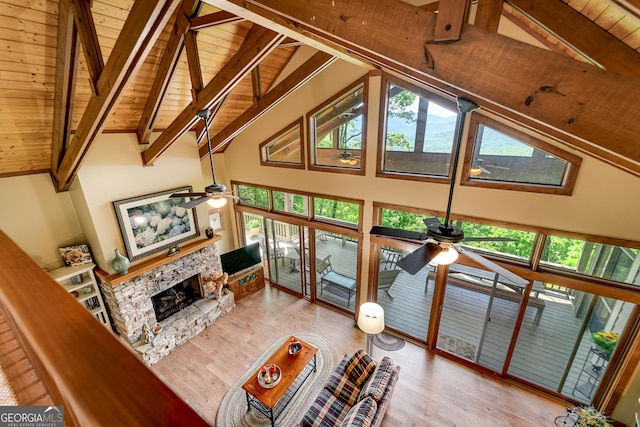 4 Dean Ln, Tiger, GA 30576 - living room with a ceiling fan, a wooden ceiling with exposed beams, wood finished floors, a stone fireplace, and healthy amount of natural light