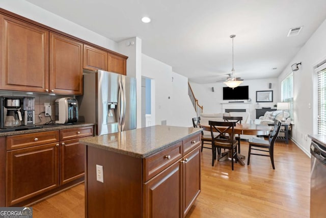 1609 Vinery Ln SE, Mableton, GA 30126 - kitchen with appliances with stainless steel finishes, a kitchen island, light wood finished floors, dark stone counters, and brown cabinets