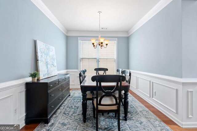 1609 Vinery Ln SE, Mableton, GA 30126 - dining space featuring a chandelier, ornamental molding, a decorative wall, a wainscoted wall, and dark wood-style floors