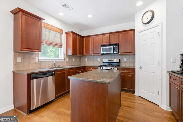 1609 Vinery Ln SE, Mableton, GA 30126 - kitchen featuring stainless steel appliances, light wood-style floors, decorative backsplash, stone countertops, and a kitchen island