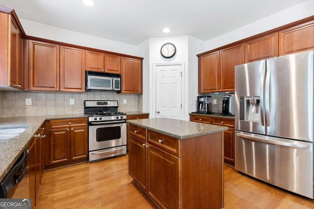 1609 Vinery Ln SE, Mableton, GA 30126 - kitchen with appliances with stainless steel finishes, stone countertops, light wood-style floors, a center island, and decorative backsplash