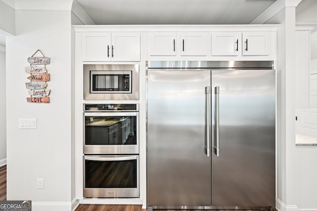4189 Brookmont Way, Auburn, GA 30011 - kitchen with built in appliances, white cabinets, wood finished floors, and light stone counters