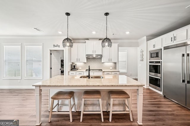 4189 Brookmont Way, Auburn, GA 30011 - kitchen with built in appliances, crown molding, under cabinet range hood, a breakfast bar area, and backsplash