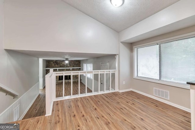 5215 Mainstreet Park Dr, Stone Mountain, GA 30088 - empty room featuring wood finished floors, ceiling fan, lofted ceiling, and a textured ceiling