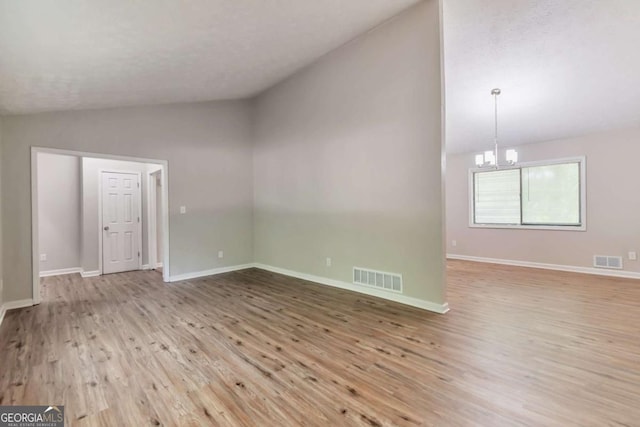 5215 Mainstreet Park Dr, Stone Mountain, GA 30088 - unfurnished living room with vaulted ceiling, a chandelier, and light wood-type flooring