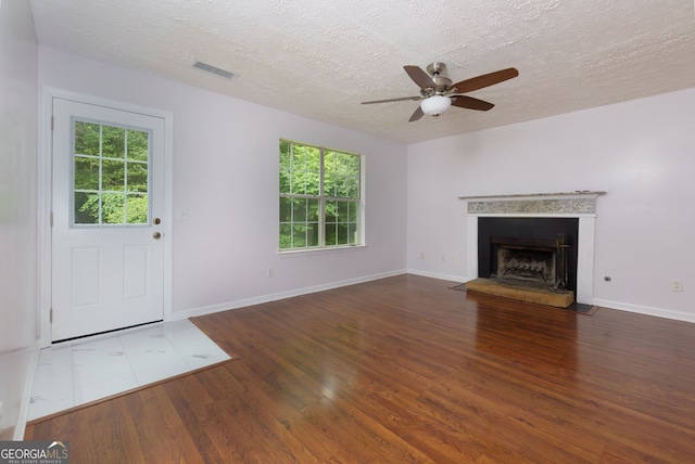 552 Caseys Xing, Winder, GA 30680 - unfurnished living room featuring a ceiling fan, wood finished floors, plenty of natural light, a textured ceiling, and a fireplace with raised hearth
