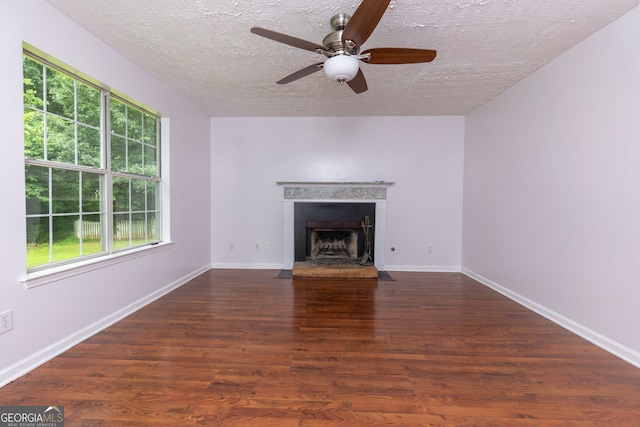 552 Caseys Xing, Winder, GA 30680 - unfurnished living room featuring a textured ceiling, a ceiling fan, a fireplace with flush hearth, and wood finished floors