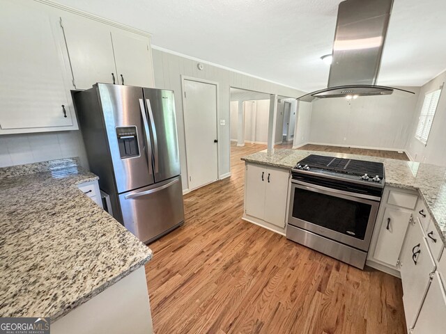 314 Pine St, Barnesville, GA 30204 - kitchen with appliances with stainless steel finishes, island range hood, light wood-type flooring, ornamental molding, and white cabinetry