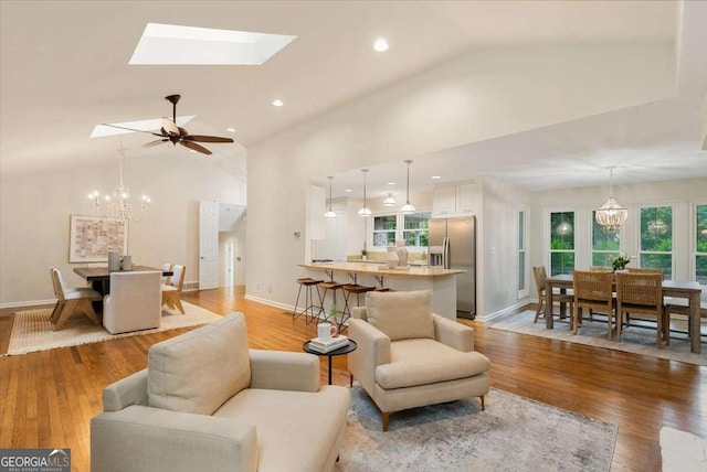 5114 N Ivy Rd NE, Atlanta, GA 30342 - living room with vaulted ceiling, a chandelier, light wood-style flooring, a skylight, and recessed lighting