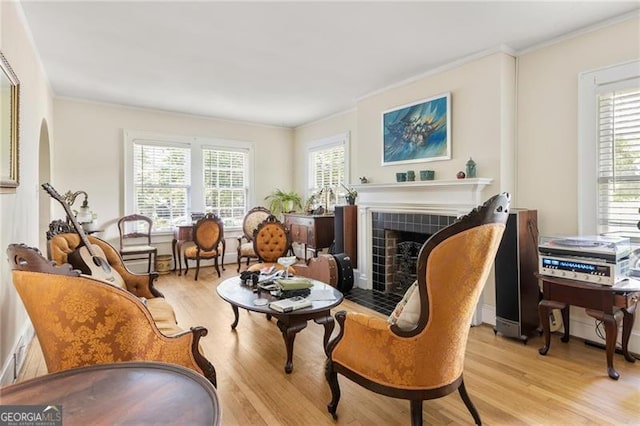 348 7th St NE, Atlanta, GA 30308 - living area featuring crown molding, light wood finished floors, a tile fireplace, and arched walkways
