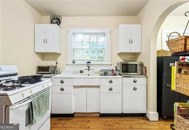 348 7th St NE, Atlanta, GA 30308 - kitchen featuring white gas range oven, stainless steel microwave, white cabinets, light wood-style floors, and light countertops