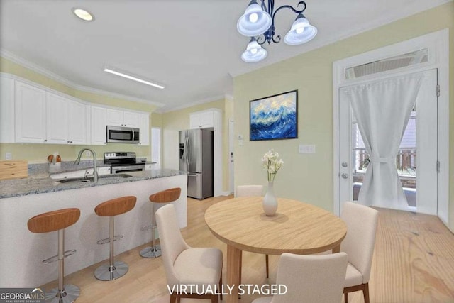 4206 Moccasin Trl, Woodstock, GA 30189 - kitchen featuring stainless steel appliances, white cabinets, light wood-style floors, crown molding, and stone countertops