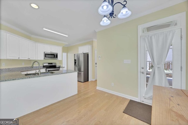 4206 Moccasin Trl, Woodstock, GA 30189 - kitchen with appliances with stainless steel finishes, white cabinets, crown molding, a chandelier, and light wood-type flooring