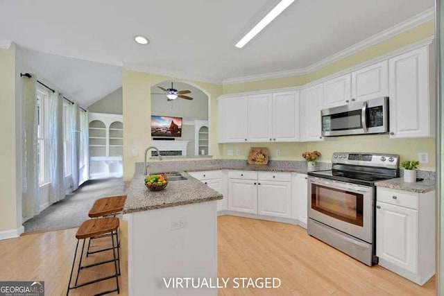 4206 Moccasin Trl, Woodstock, GA 30189 - kitchen with appliances with stainless steel finishes, white cabinetry, ceiling fan, a breakfast bar, and ornamental molding