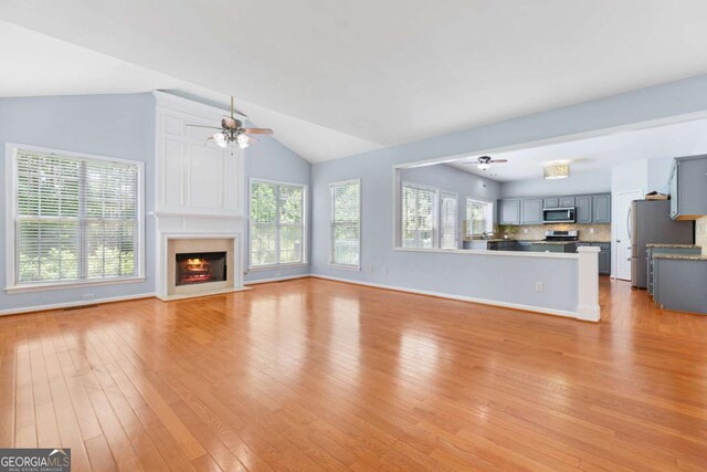 5003 Pacific Dunes Dr, Suwanee, GA 30024 - unfurnished living room featuring ceiling fan, vaulted ceiling, light wood-style floors, healthy amount of natural light, and a high end fireplace