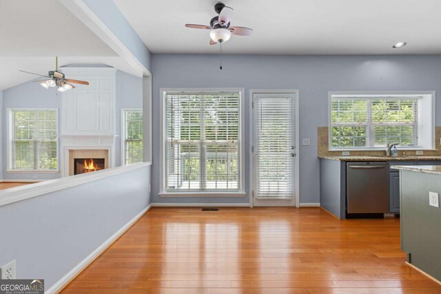 5003 Pacific Dunes Dr, Suwanee, GA 30024 - kitchen featuring dishwasher, ceiling fan, light wood-style flooring, and a lit fireplace
