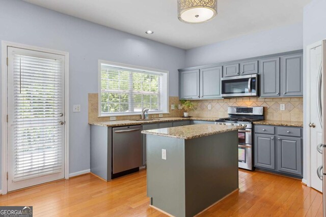 5003 Pacific Dunes Dr, Suwanee, GA 30024 - kitchen with appliances with stainless steel finishes, gray cabinets, decorative backsplash, a kitchen island, and recessed lighting