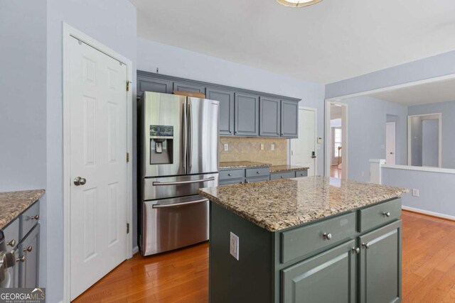 5003 Pacific Dunes Dr, Suwanee, GA 30024 - kitchen featuring stainless steel fridge, wood finished floors, tasteful backsplash, a kitchen island, and light stone countertops