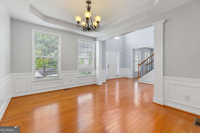 5003 Pacific Dunes Dr, Suwanee, GA 30024 - unfurnished room featuring a chandelier, a tray ceiling, wainscoting, light wood finished floors, and a decorative wall