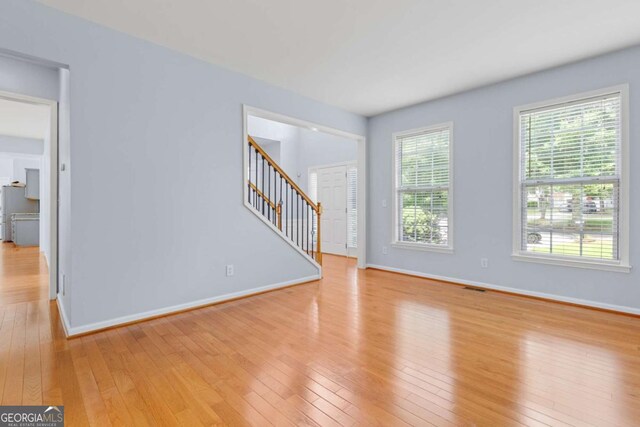 5003 Pacific Dunes Dr, Suwanee, GA 30024 - unfurnished living room with light wood finished floors and stairway