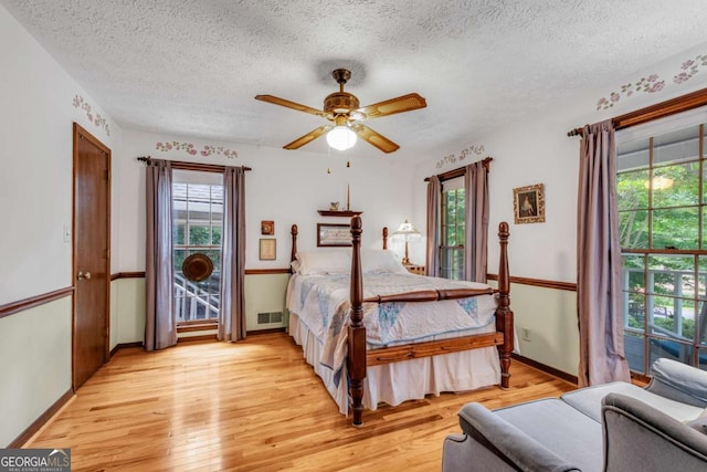 3754 Wyntuck Cir NW, Kennesaw, GA 30152 - bedroom featuring light wood-style flooring, multiple windows, a textured ceiling, and a ceiling fan