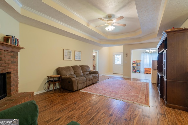 3030 Thornberry Cir, Phenix City, AL 36867 - living room featuring a tray ceiling, ornamental molding, a chandelier, a brick fireplace, and ceiling fan