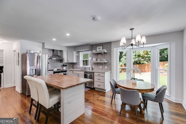 7250 Hunters Branch Dr, Atlanta, GA 30328 - kitchen with wall chimney exhaust hood, appliances with stainless steel finishes, butcher block countertops, a chandelier, and dark wood-type flooring
