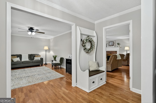 1505 Misty Valley Dr, Chatsworth, GA 30705 - entrance foyer featuring light wood-type flooring, a textured ceiling, a fireplace, a ceiling fan, and crown molding