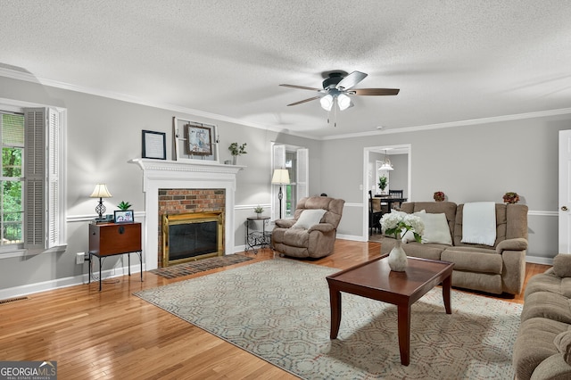 1505 Misty Valley Dr, Chatsworth, GA 30705 - living room featuring ceiling fan, wood finished floors, a textured ceiling, a brick fireplace, and ornamental molding
