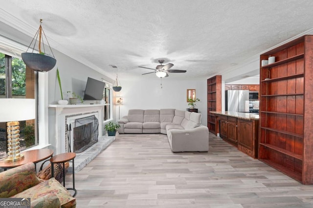 834 Lake Hollow Blvd SW, Marietta, GA 30064 - living room with a ceiling fan, light wood-style flooring, a fireplace with raised hearth, a textured ceiling, and ornamental molding